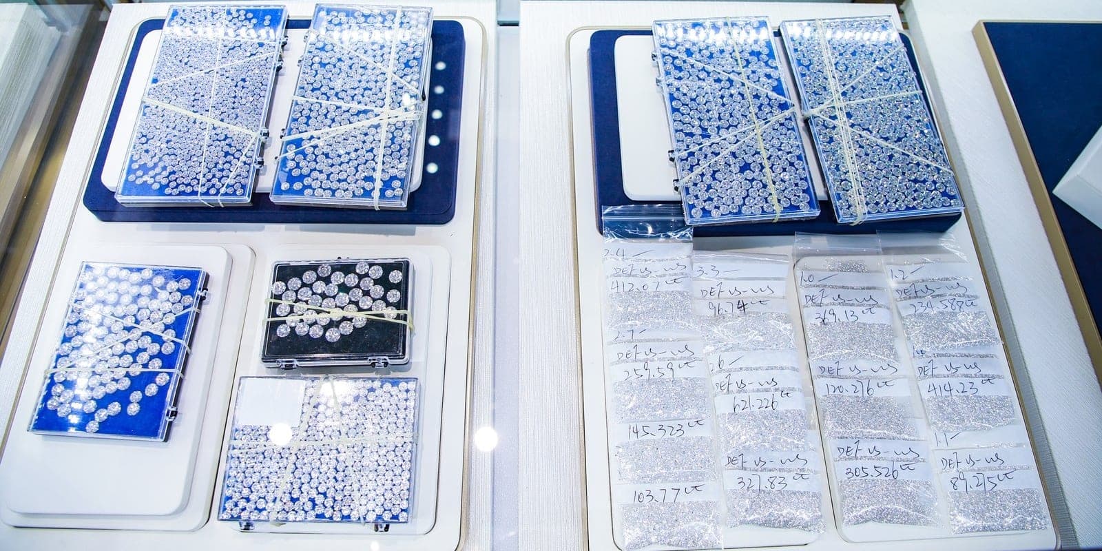 Polished diamonds sorted into parcel papers and boxes, each marked with its color, clarity and carat weight